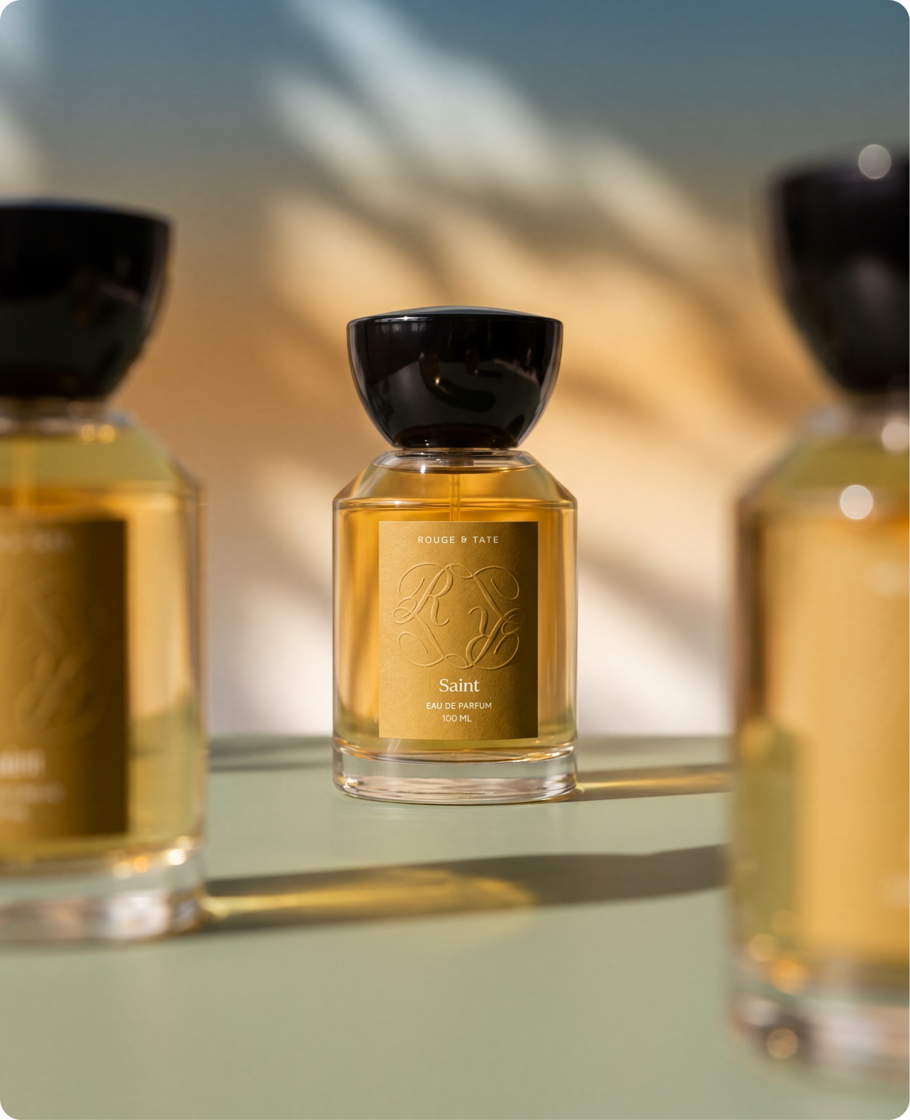 Rouge & Tate — the Saint bottle in warm afternoon light, gold label glowing against soft shadow leaves