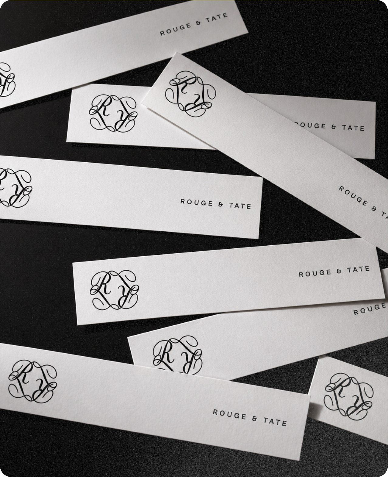 Rouge & Tate — scattered print collateral: paper strips carrying the R&T monogram and wordmark