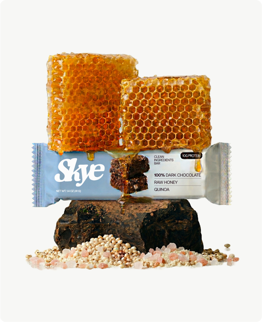 Skye — a protein bar with stacked honeycomb on a raw stone, scattered puffed quinoa and salt, showcasing the clean-ingredient story of dark chocolate, raw honey, and quinoa