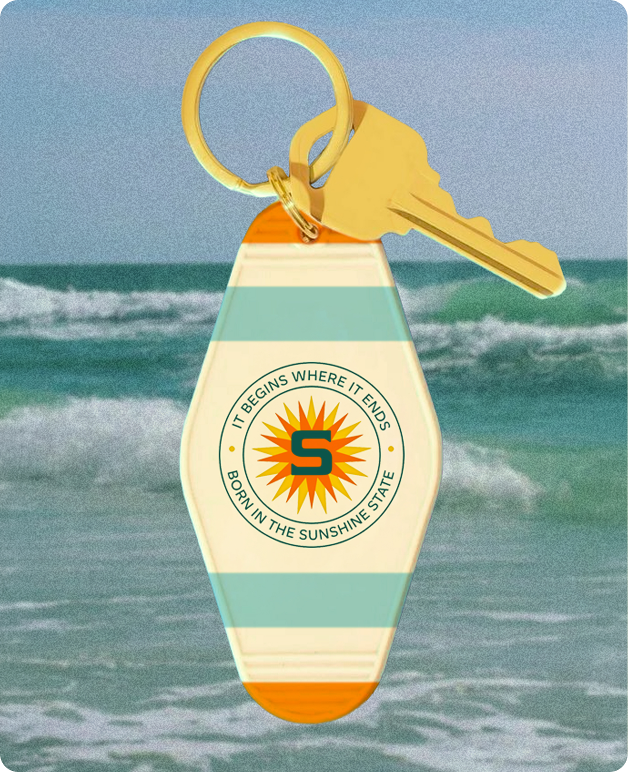 Sollos — a retro motel-style keychain with the Sollos sunburst medallion and key, held against the ocean