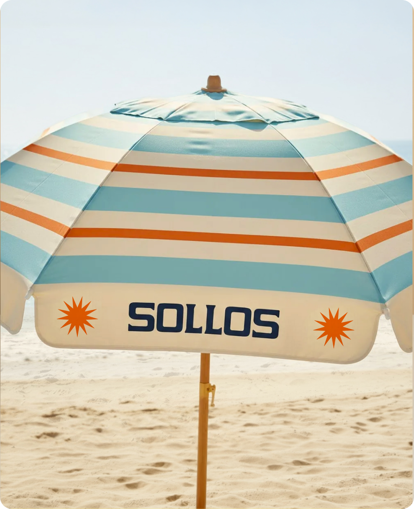 Sollos — a beach umbrella in cream, sky-blue, and orange stripes with the Sollos wordmark and sunburst, planted in the sand