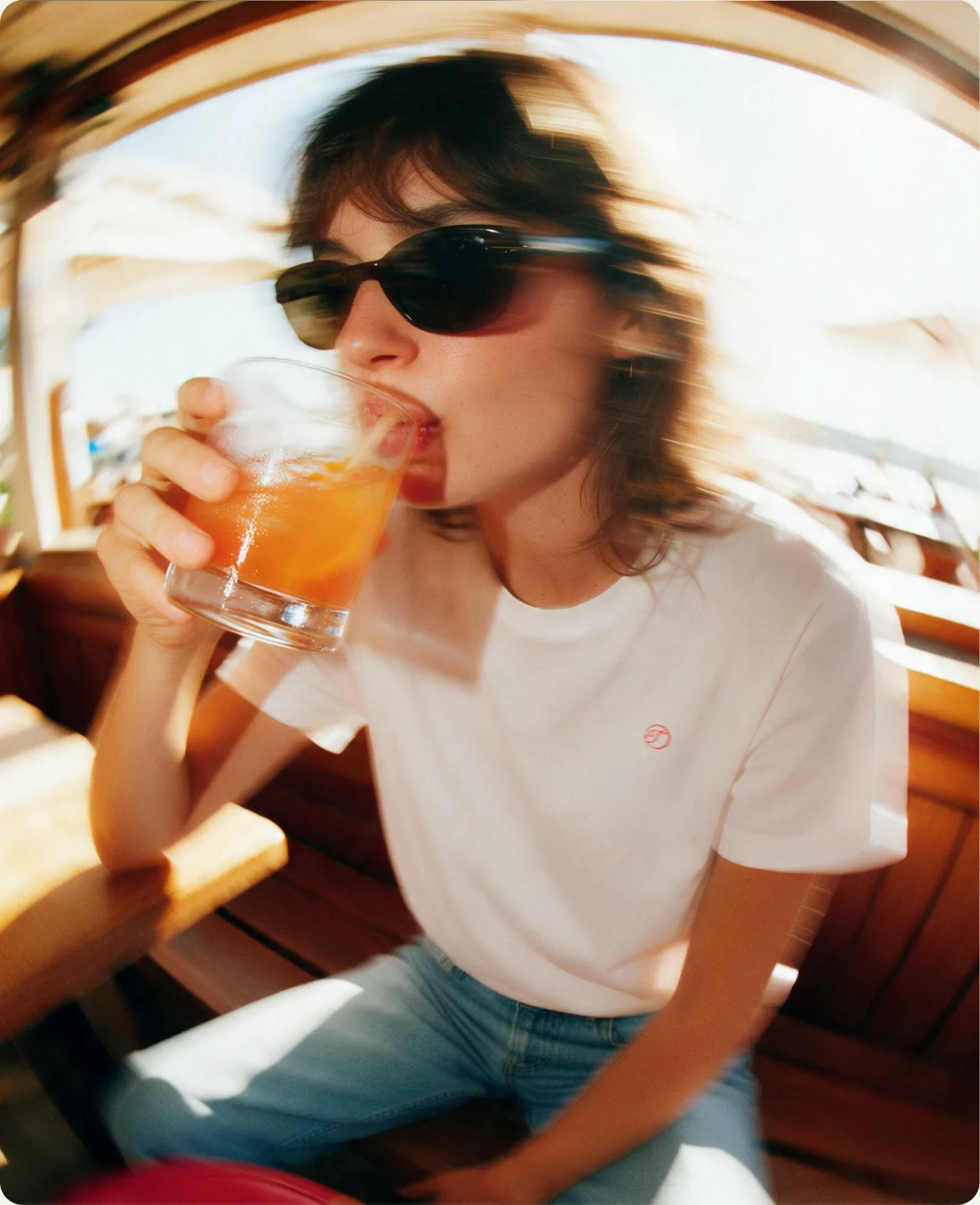 Tivo: a woman in sunglasses and a white t-shirt drinking an orange Tivo serve from a tumbler in warm afternoon light